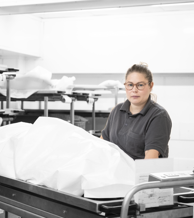 Marleen steht vor einer Bridge, auf der ein Tuch über einer Leiche liegt.