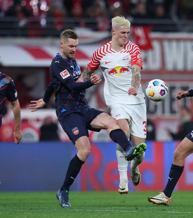 Heidenheims Kevin Sessa und Leipzigs Benjamin Sesko kämpfen am 02.12.2023 um den Ball.