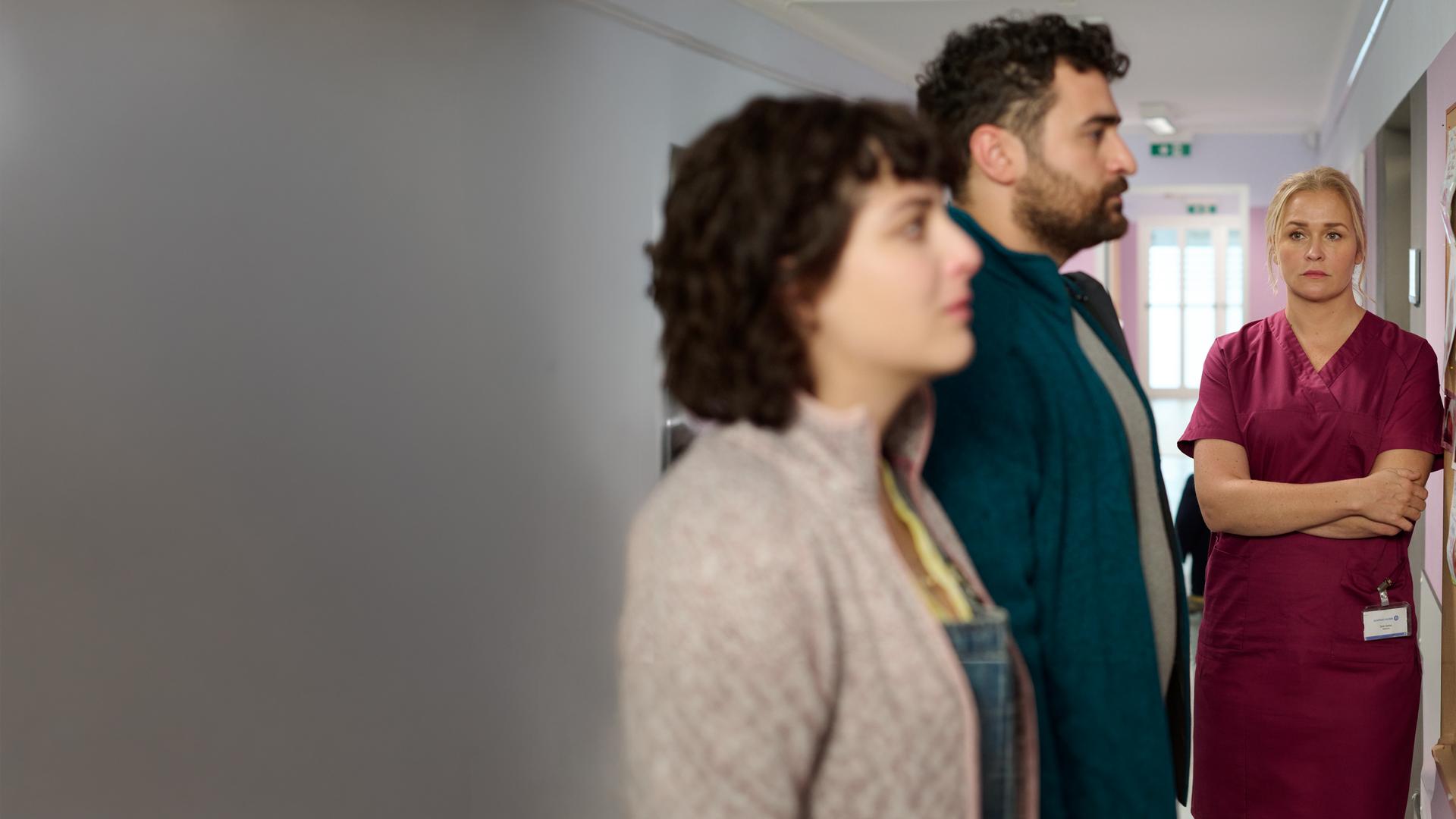 "Lena Lorenz - Das Leben ist jetzt": In einem Krankenhausflur stehen Ina (Anna Werner Friedmann) und Felipe Fromme (Ugur Kaya) vor einer Pinwand mit Babyfotos, die sie mit verzweifeltem Gesichtsausdruck betrachten. Lena Lorenz (Judith Hoersch) steht mit verschränkten Armen daneben und schaut das Paar traurig an.