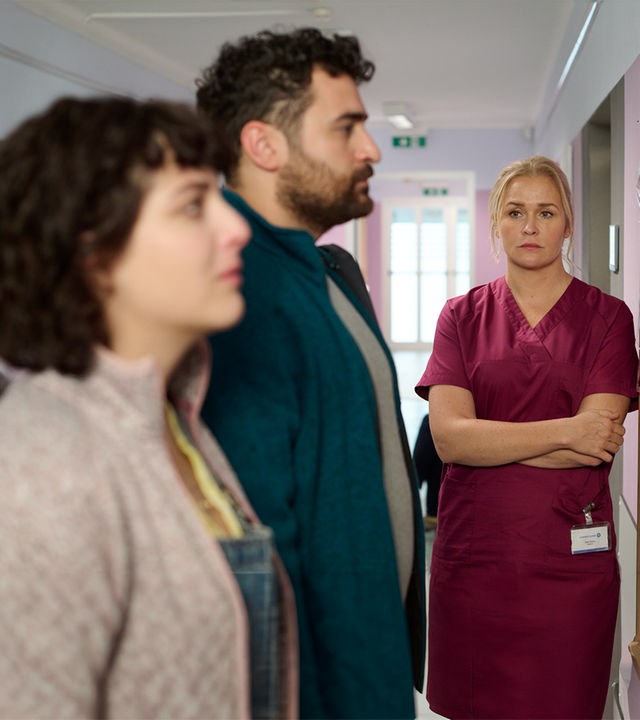 "Lena Lorenz - Das Leben ist jetzt": In einem Krankenhausflur stehen Ina (Anna Werner Friedmann) und Felipe Fromme (Ugur Kaya) vor einer Pinwand mit Babyfotos, die sie mit verzweifeltem Gesichtsausdruck betrachten. Lena Lorenz (Judith Hoersch) steht mit verschränkten Armen daneben und schaut das Paar traurig an.