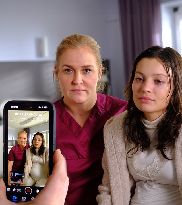 "Lena Lorenz - Vor aller Augen": In einem Krankenzimmer sitzen Lena Lorenz (Judith Hoersch) und Nadja Brettschneider (Vivien König) nebeneinander auf einem Bett. Beide schauen in eine Handykamera, die auf sie gerichtet wird.