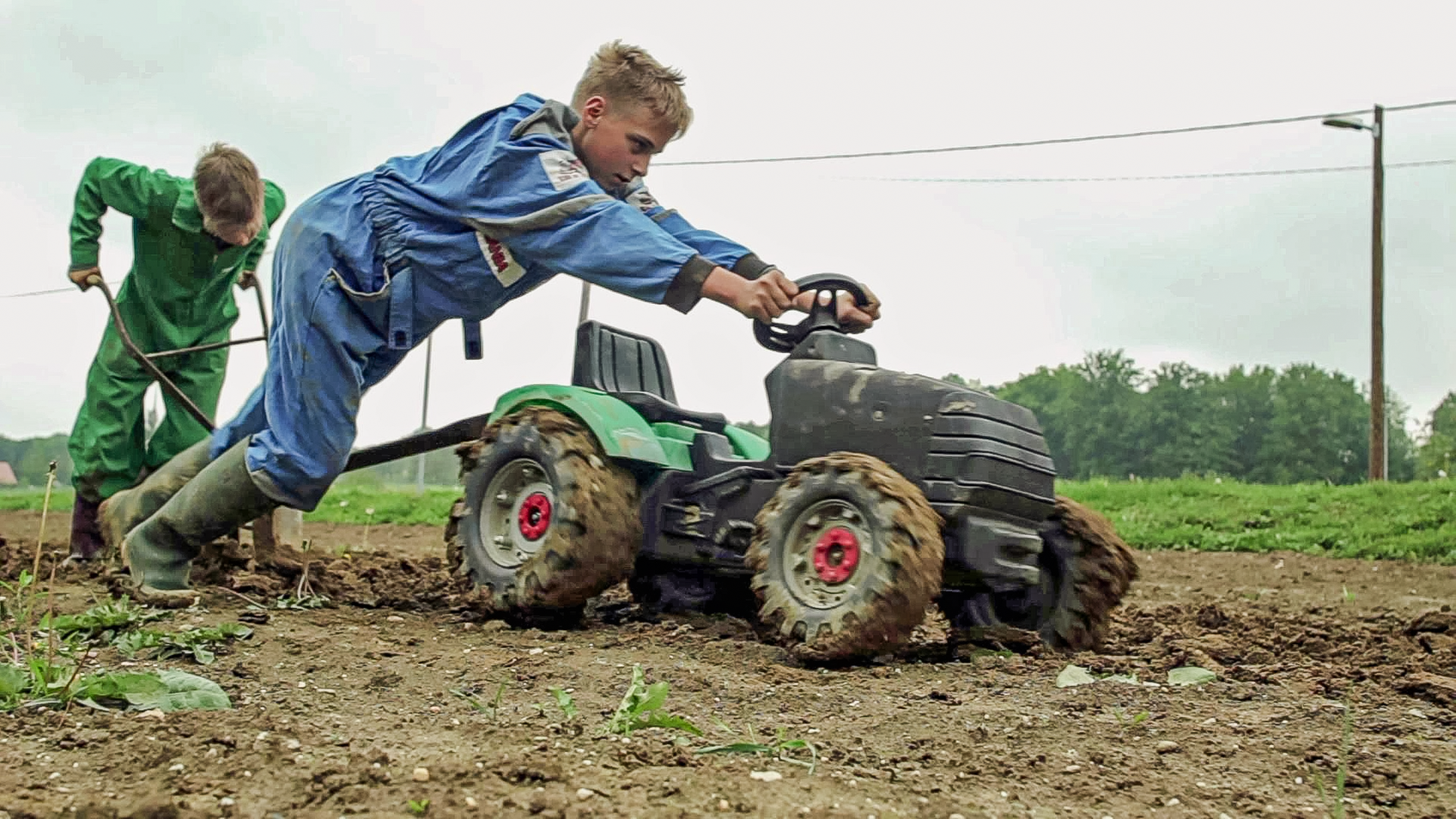 Leon und Jan pflügen das Feld mit ihrem Kindertraktor
