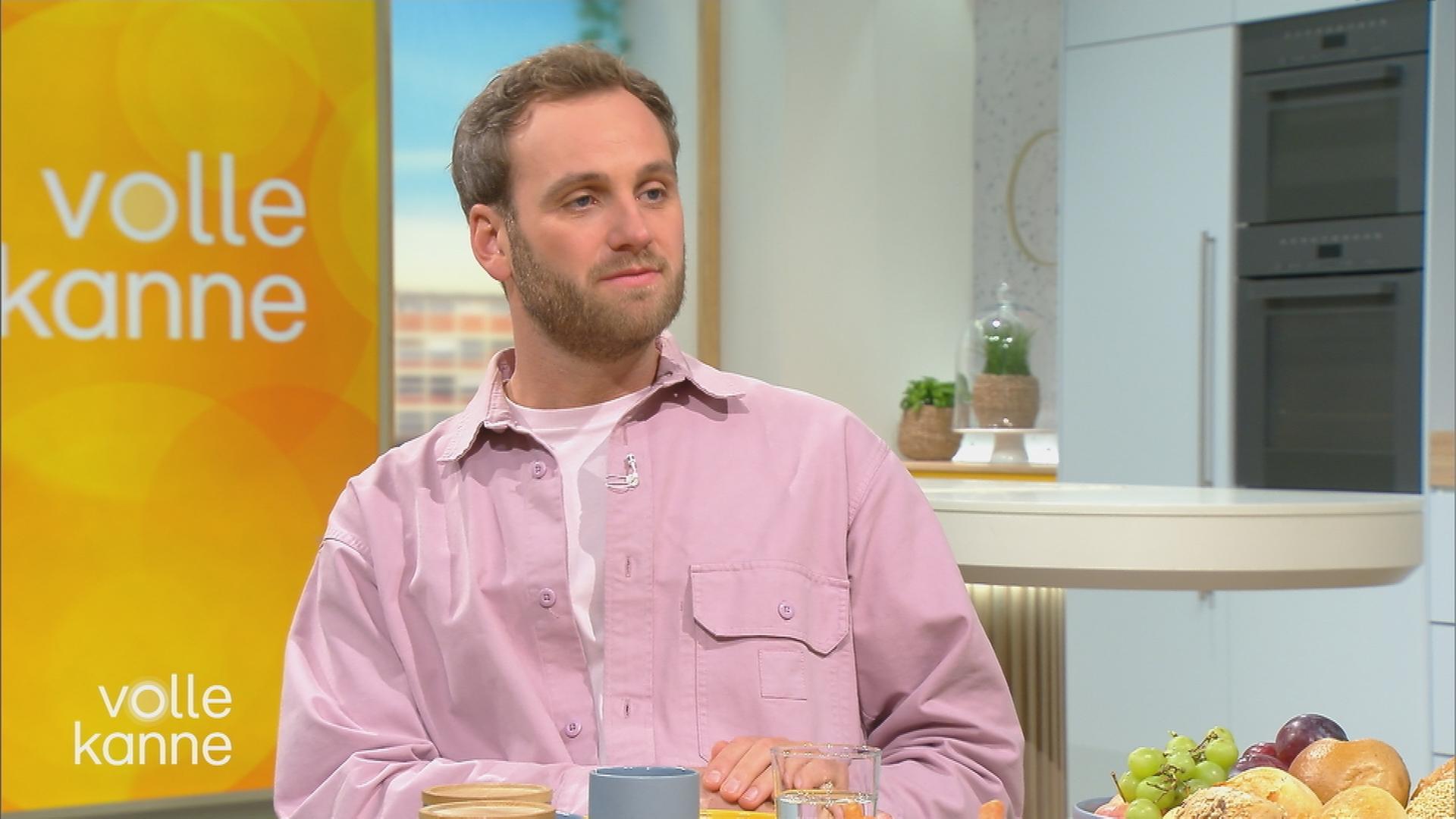 Psychologe Leon Windscheid im pinken Hemd sitzt im Volle-Kanne-Studio