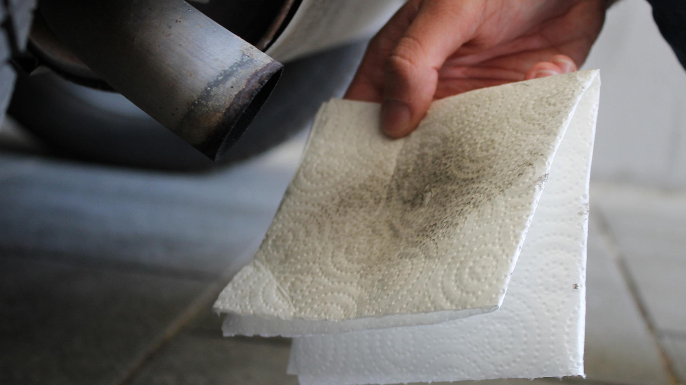 Ein verfärbtes Taschentuch am Auspuff eines Autos