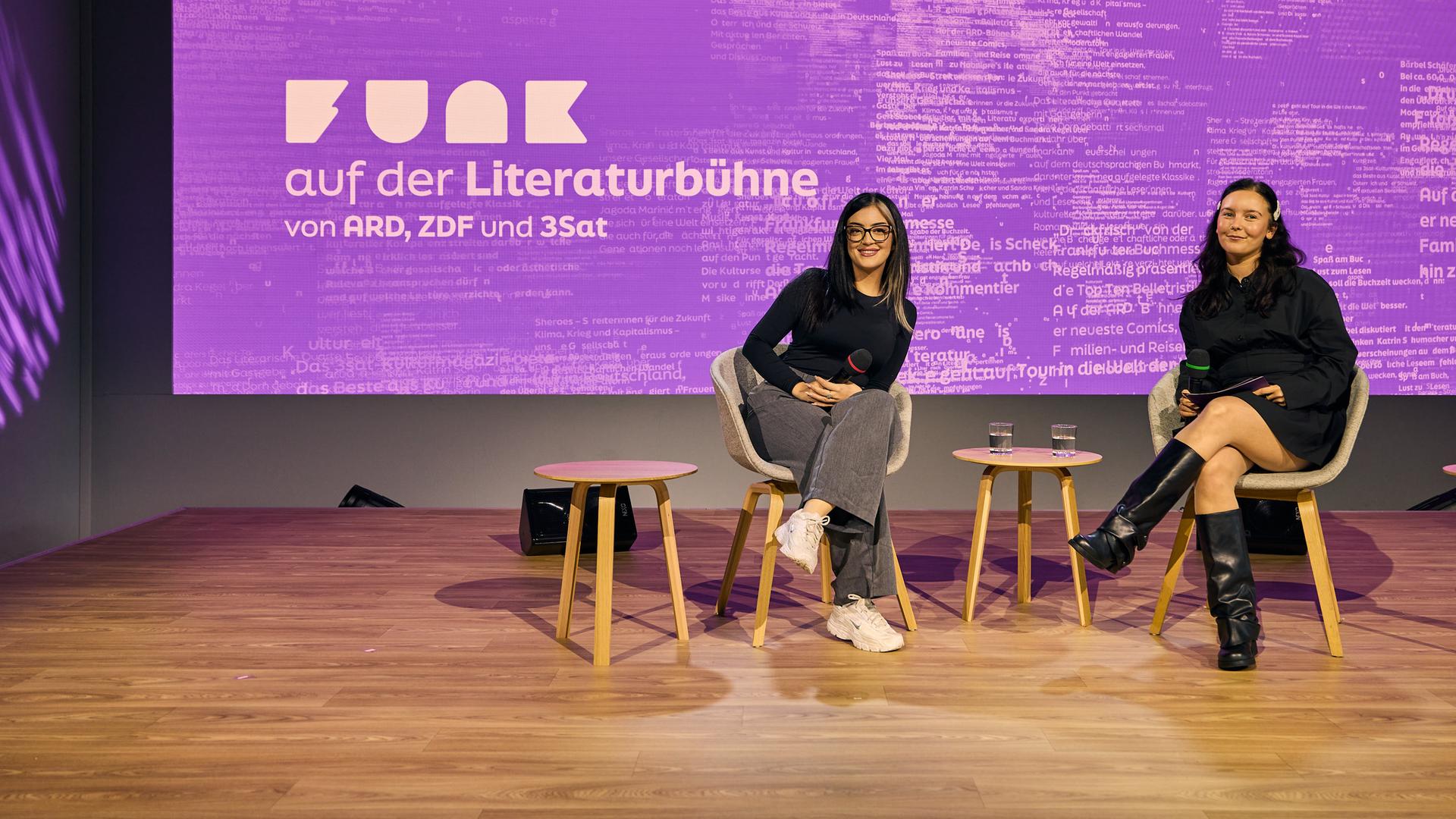 Zwei junge Frauen sitzen auf einer Bühne