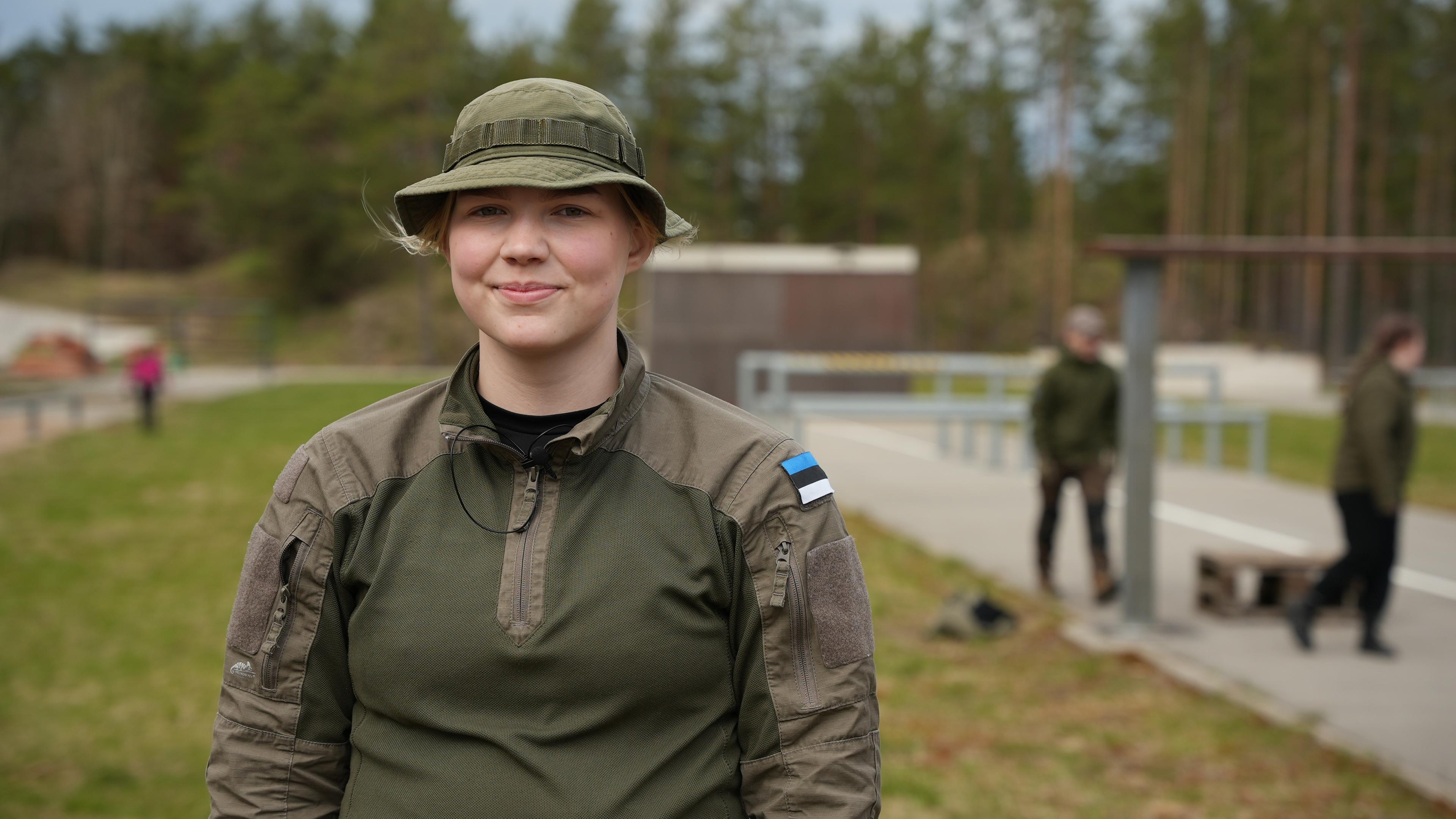 Ein Mädchen in Militärskleidung steht auf dem Übungsgelände 
