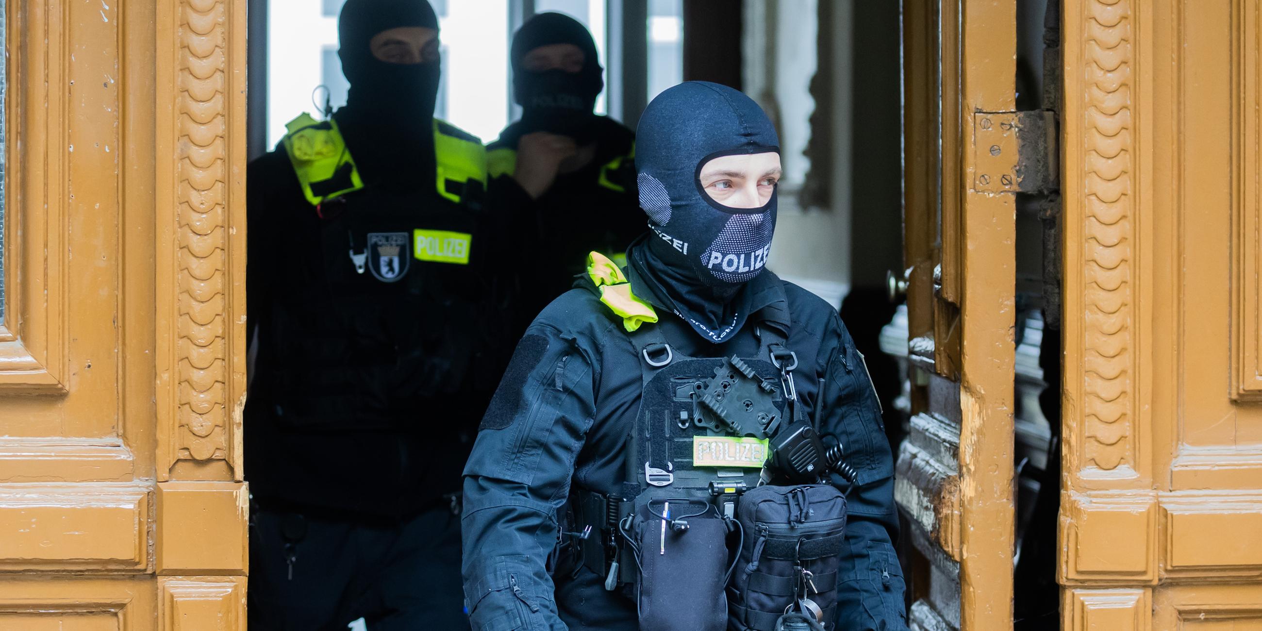 Polizisten kommen bei einer Hausdurchsuchung in Berlin-Kreuzberg aus einem Gebäude.