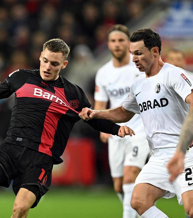 Bayer Leverkusen's Florian Wirtz (C) und Freiburg's Nicolas Hoefler (R) im Zweikampf am 29.10.23.