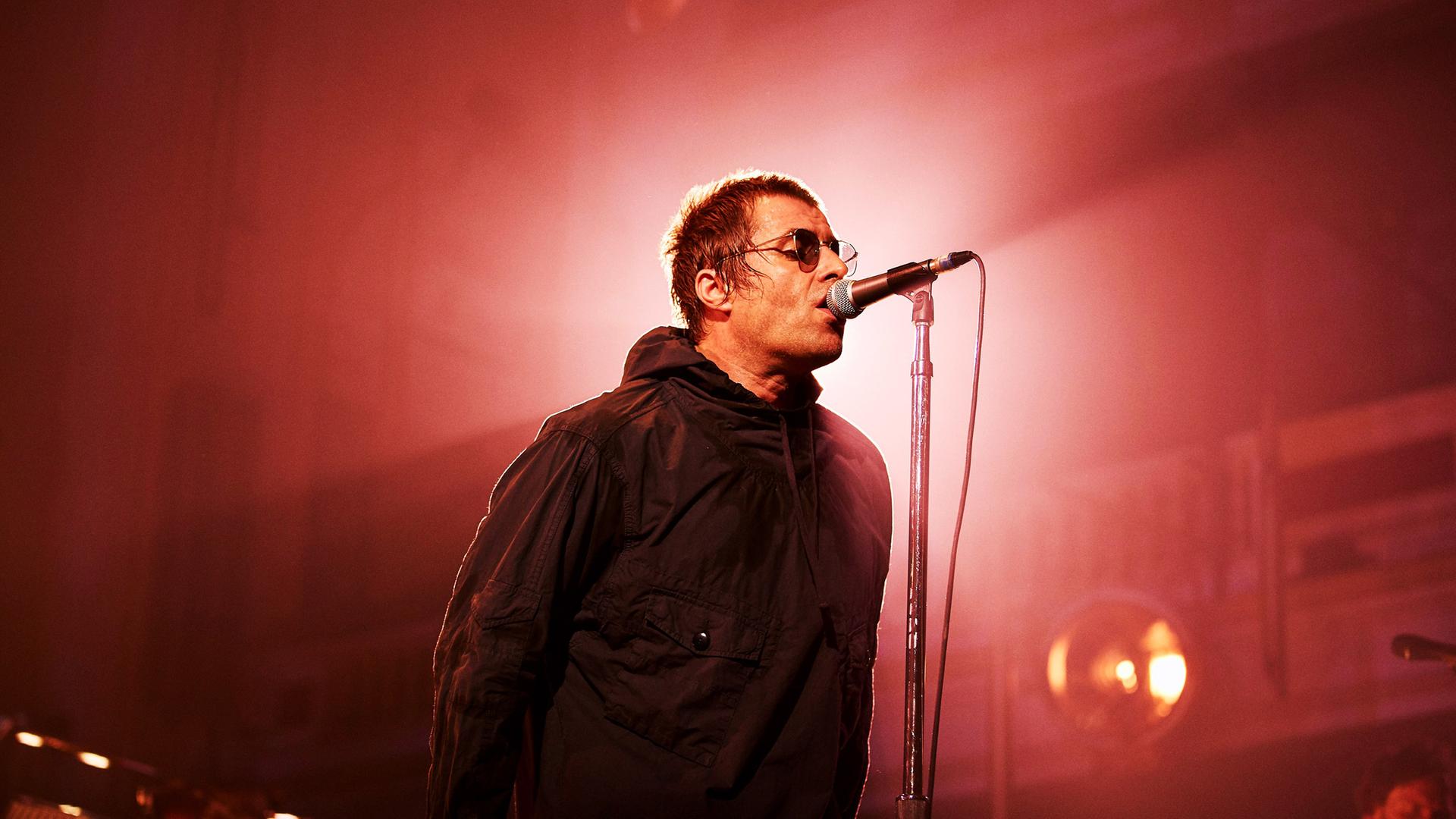 Liam Gallagher singt mit Sonnenbrille ins Mikro.