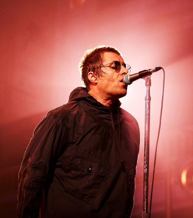 Liam Gallagher singt mit Sonnenbrille ins Mikro.