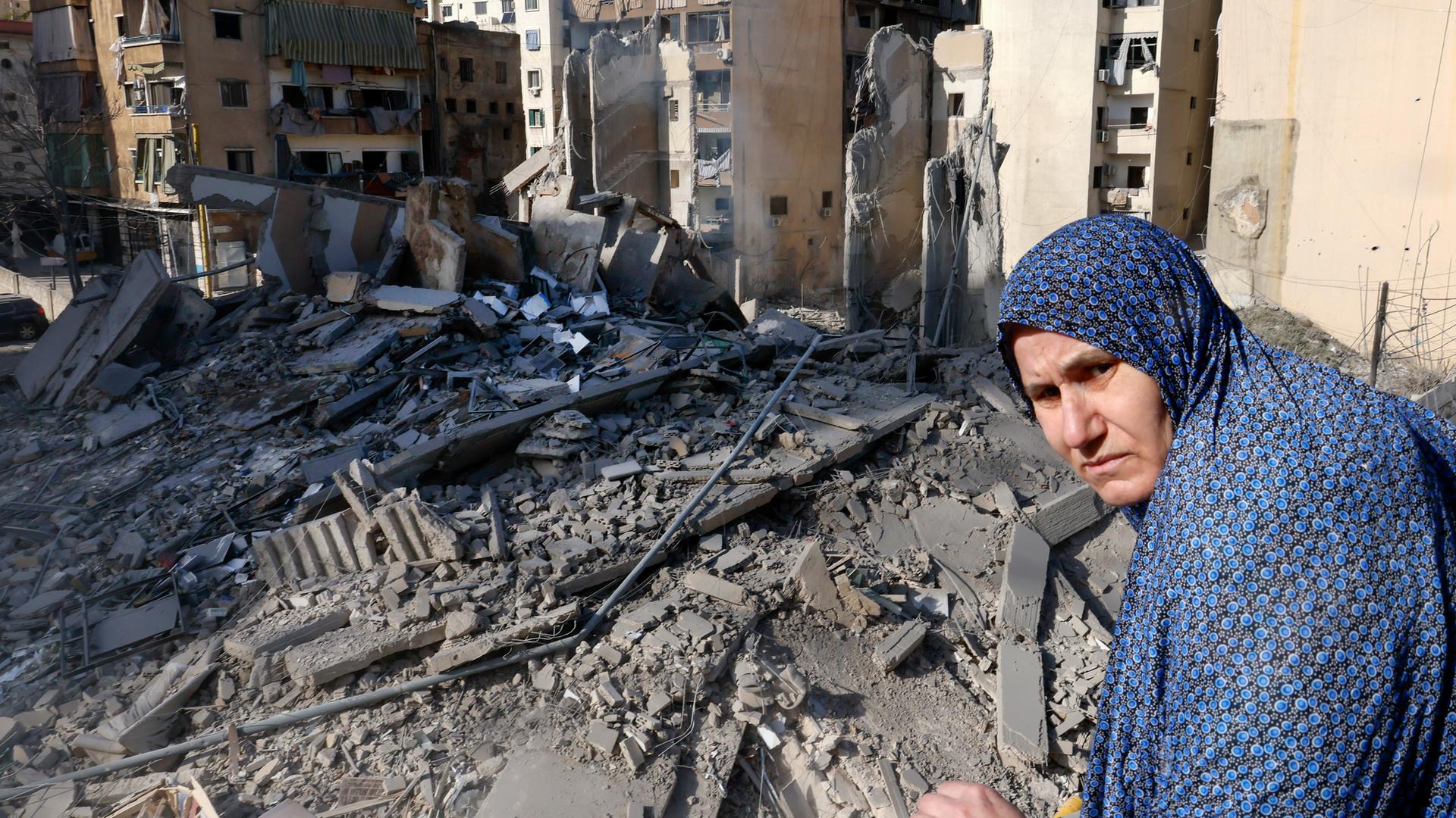 Frau schaut auf Trümmer eines zerstörten Wohnhauses