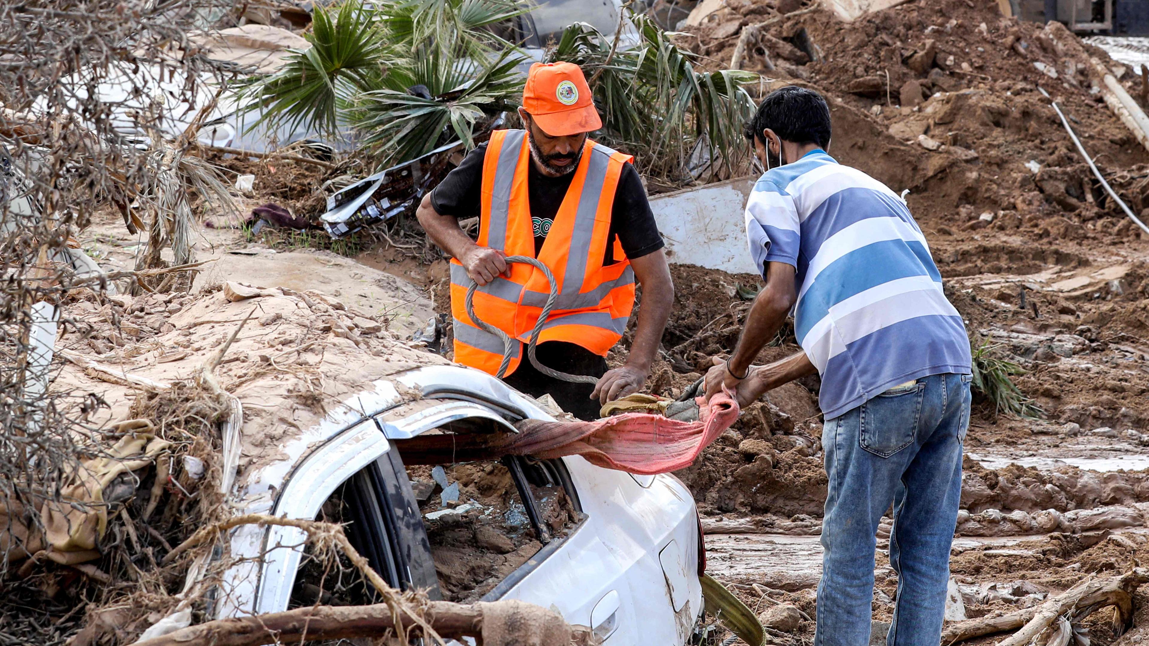 Flut in Libyen. Männer versuchen ein Auto auf die Bergung vorzubereiten