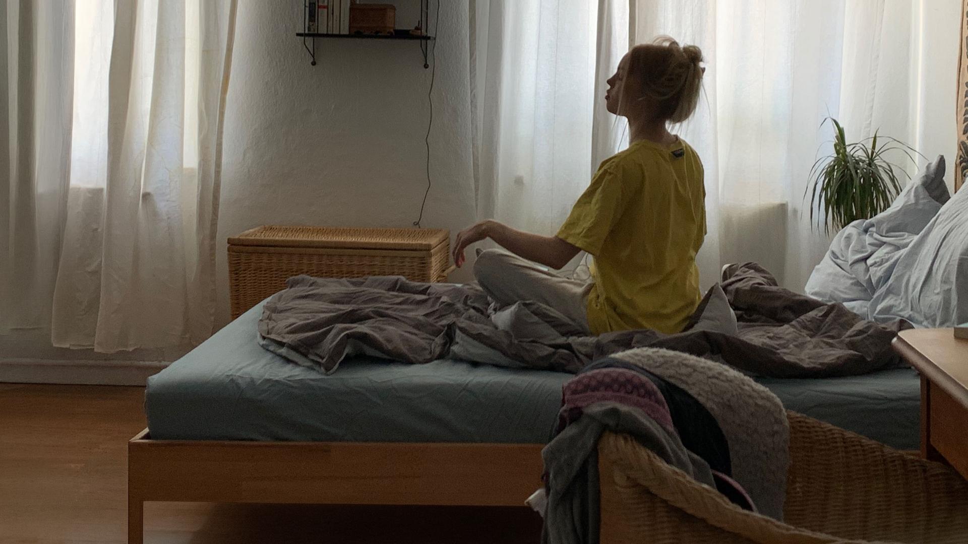 "Liebe. Jetzt! - Ja, nein, vielleicht?": Lucy (Lea Zoe Voss) sitzt mit Kopfhörern im Ohr auf ihrem Bett und versucht, meditativ zu entspannen.