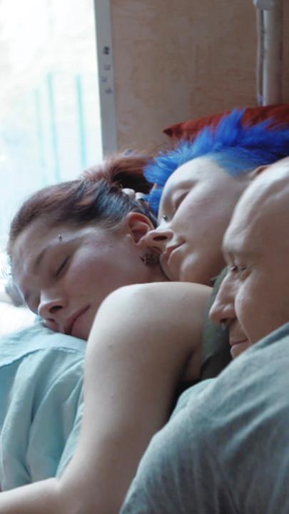 "Liebe und Sex in Russland - Tradition, Gewalt und Widerstand": Ein Mann und zwei Frauen liegen neben einem Fenster aufeinander und schlafen.