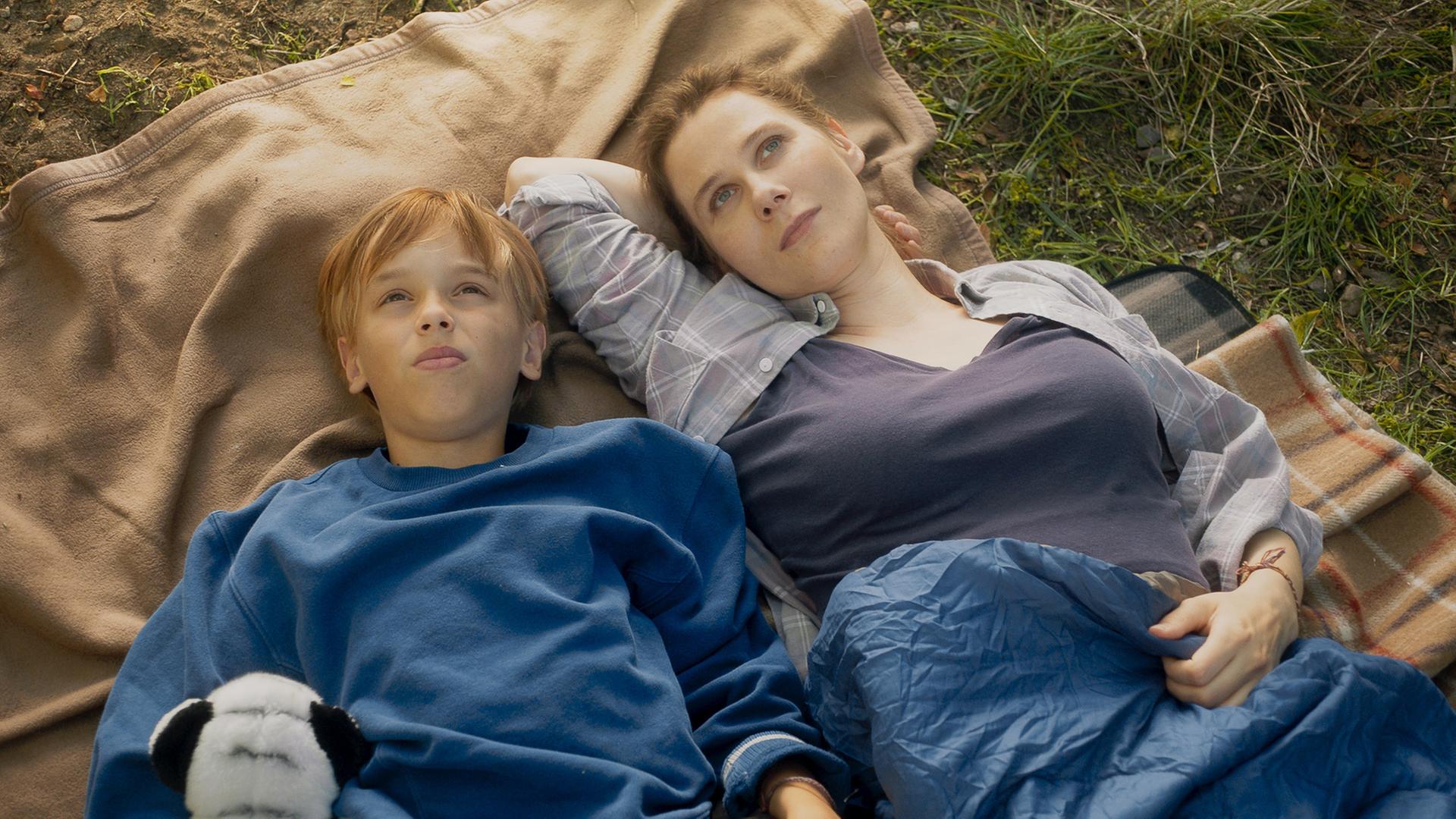 "Doktor Ballouz - Lieben und Lassen": Steffi Borgmann (Katrin Röver) liegt mit ihrem Sohn Finn (Otis Ray Whigham) auf einer Decke auf einer Wiese. Die beiden schauen verträumt in den Himmel.