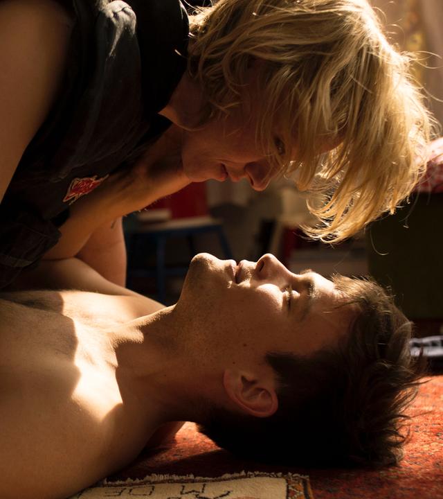 Ira (Lana Cooper) liegt auf Lenz (Eric Klotzsch) in ihrer kleinen Kreuzberger Wohnung auf dem Teppich.