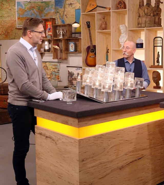 Experte Detlev Kümmel begutachtet eine "Ice Cube"-Deckenleuchte. Mit ihm am Expertenpult stehen Horst Lichter und der Verkäufer der Lampe.