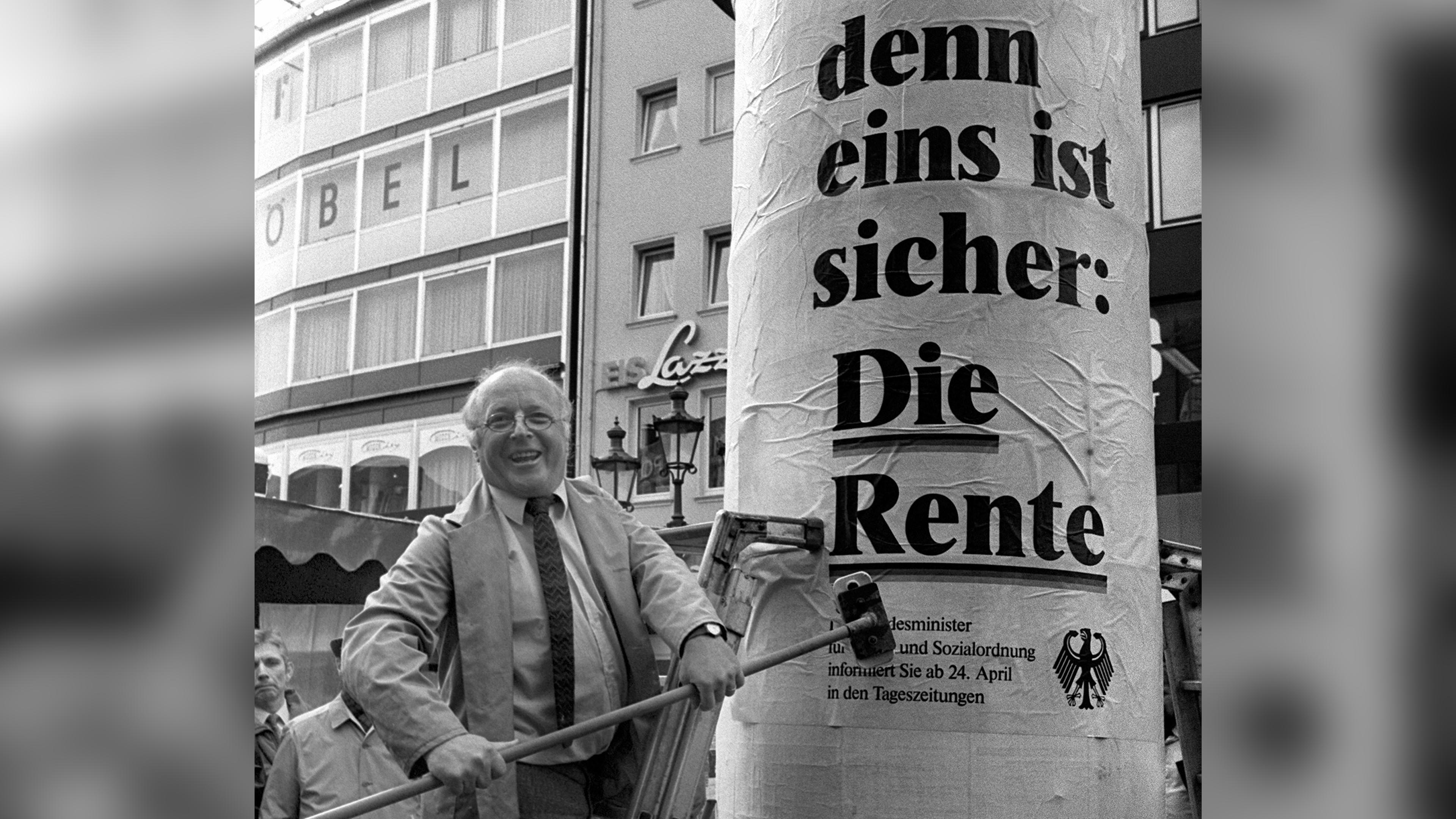 Der damalige Bundesarbeitsminister Norbert Blüm bringt eigenhändig ein Plakat mit der Aufschrift "... denn eins ist sicher: Die Rente" auf einer Litfaßsäule in Bonn an.