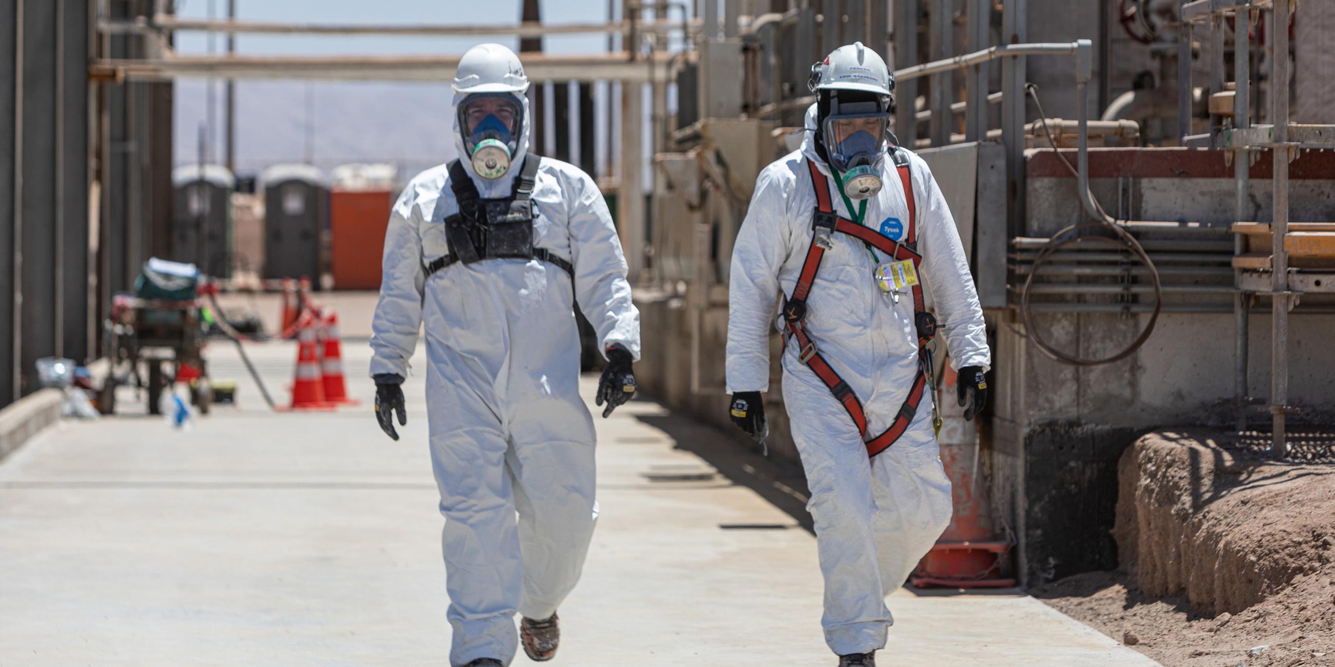 Arbeiter gehen in Schutzanzügen und mit Masken durch die Anlage zur Herstellung von Lithiumkarbonat des chilenischen Unternehmens SQM.