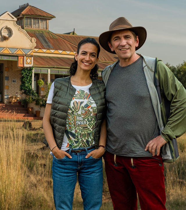 Fritz und Yasemin stehen vor einem Farmhaus in Südafrika