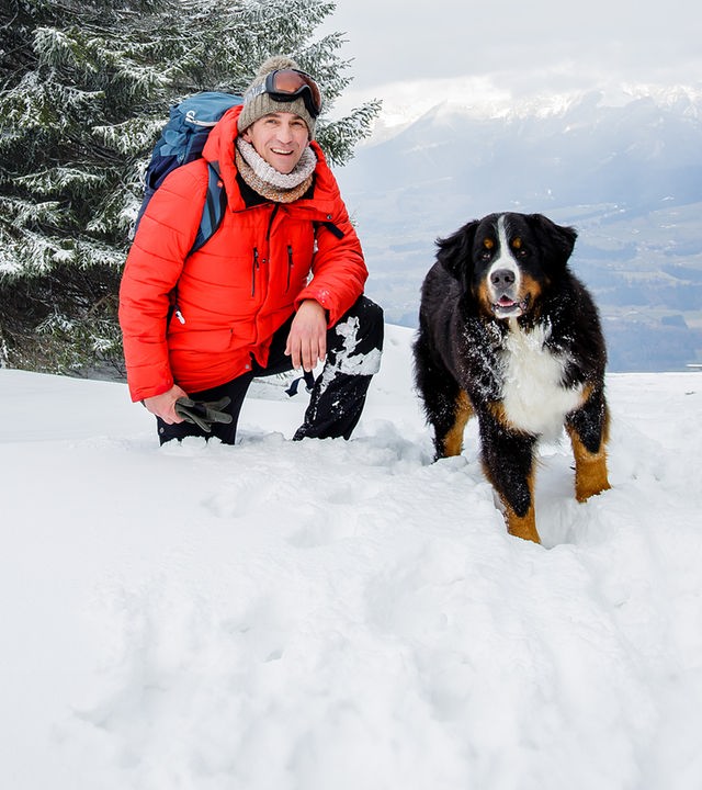 Fritz Fuchs und Keks stehen in den Bergen im Schnee