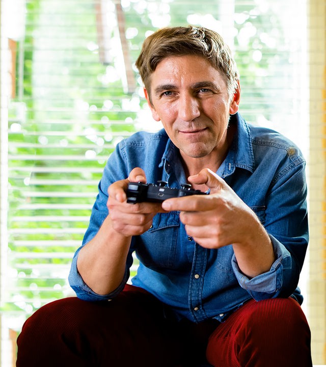 Fritz sitzt auf dem Sofa und hält einen Kontroller in der Hand