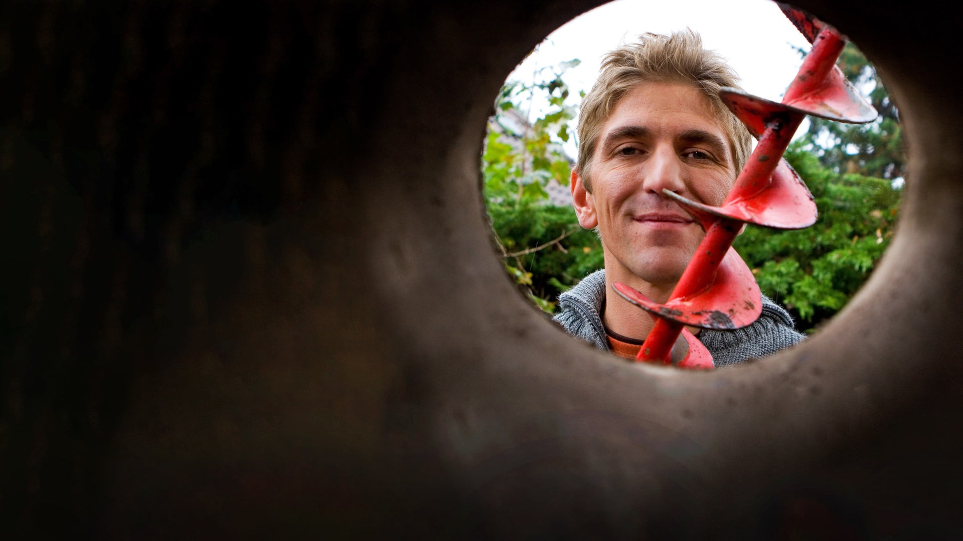 Fritz sitzt an einem Tisch vor dem Bauwagen und hält Haferkörner in seinen Händen.