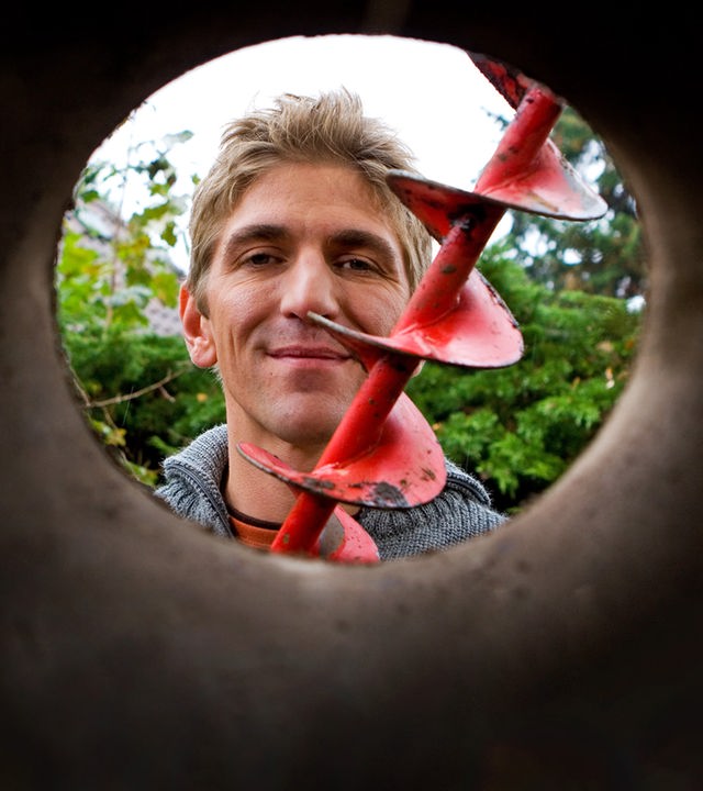 Fritz sitzt an einem Tisch vor dem Bauwagen und hält Haferkörner in seinen Händen.