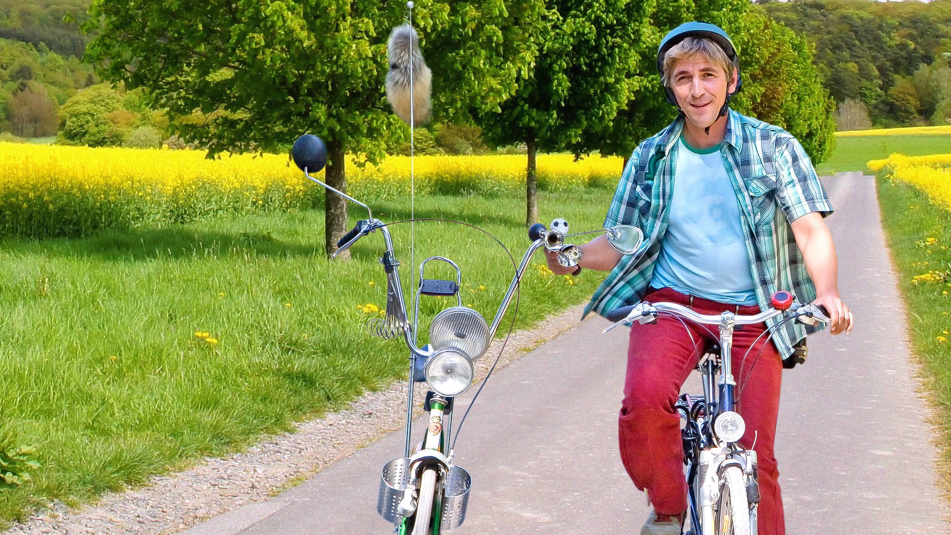 Fritz Fuchs fährt mit einem Fahrrad auf einem Radweg durch blühende Wiesen