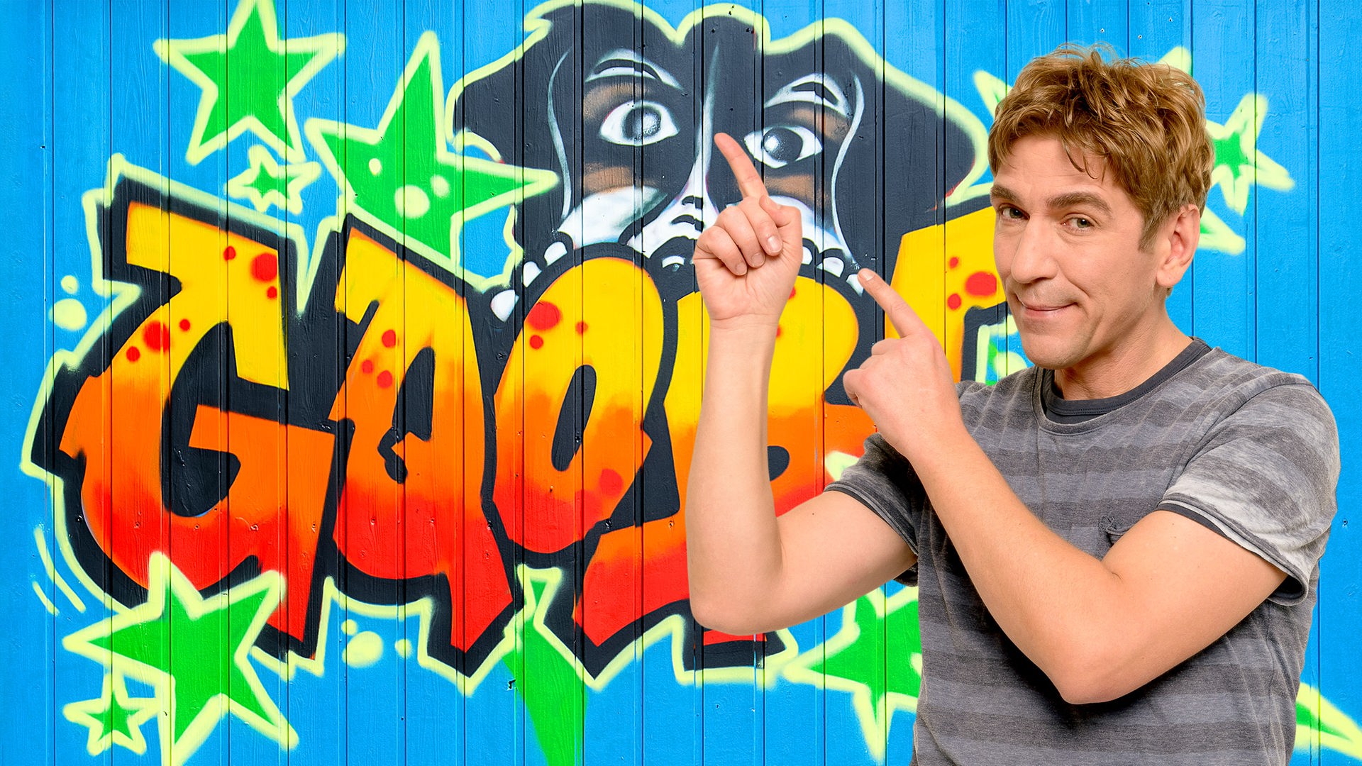 Fritz zeigt auf eine Wand mit Graffiti