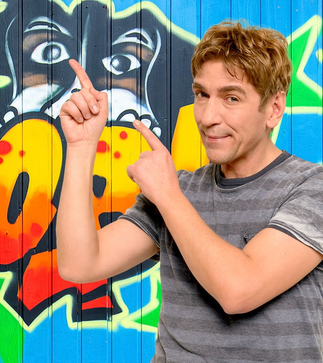 Fritz zeigt auf eine Wand mit Graffiti