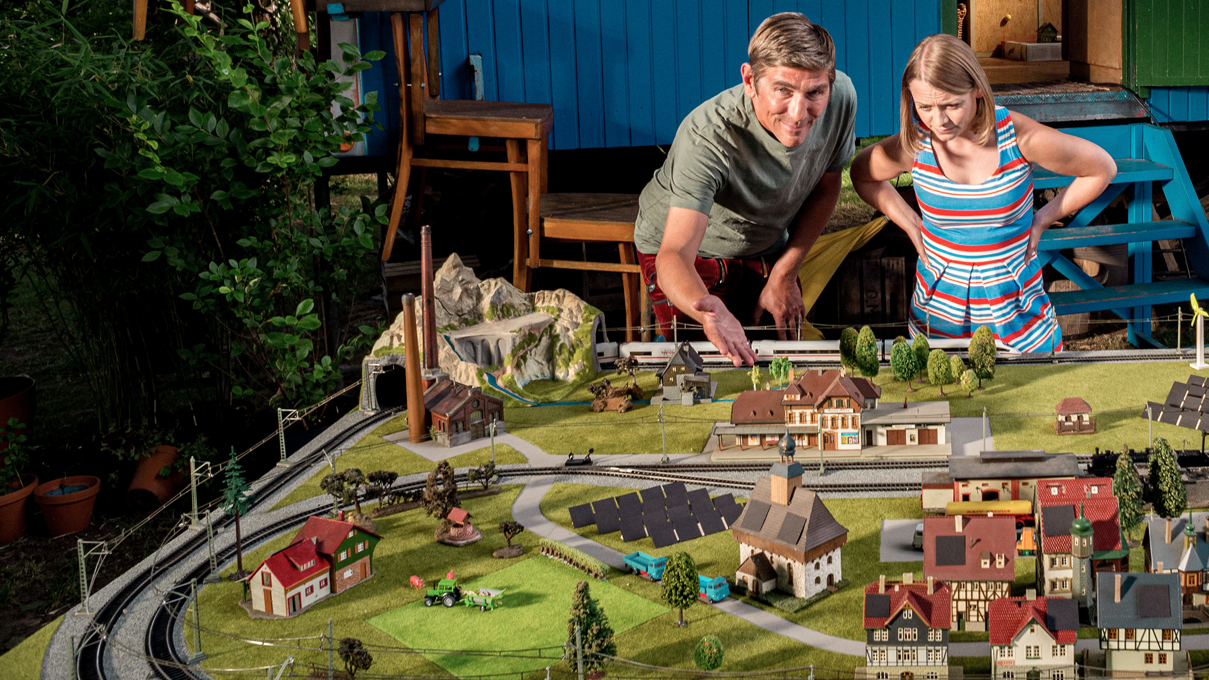 Fritz und Charlie schauen sich vor dem Bauwagen eine Modelllandschaft zu grüner Energie an