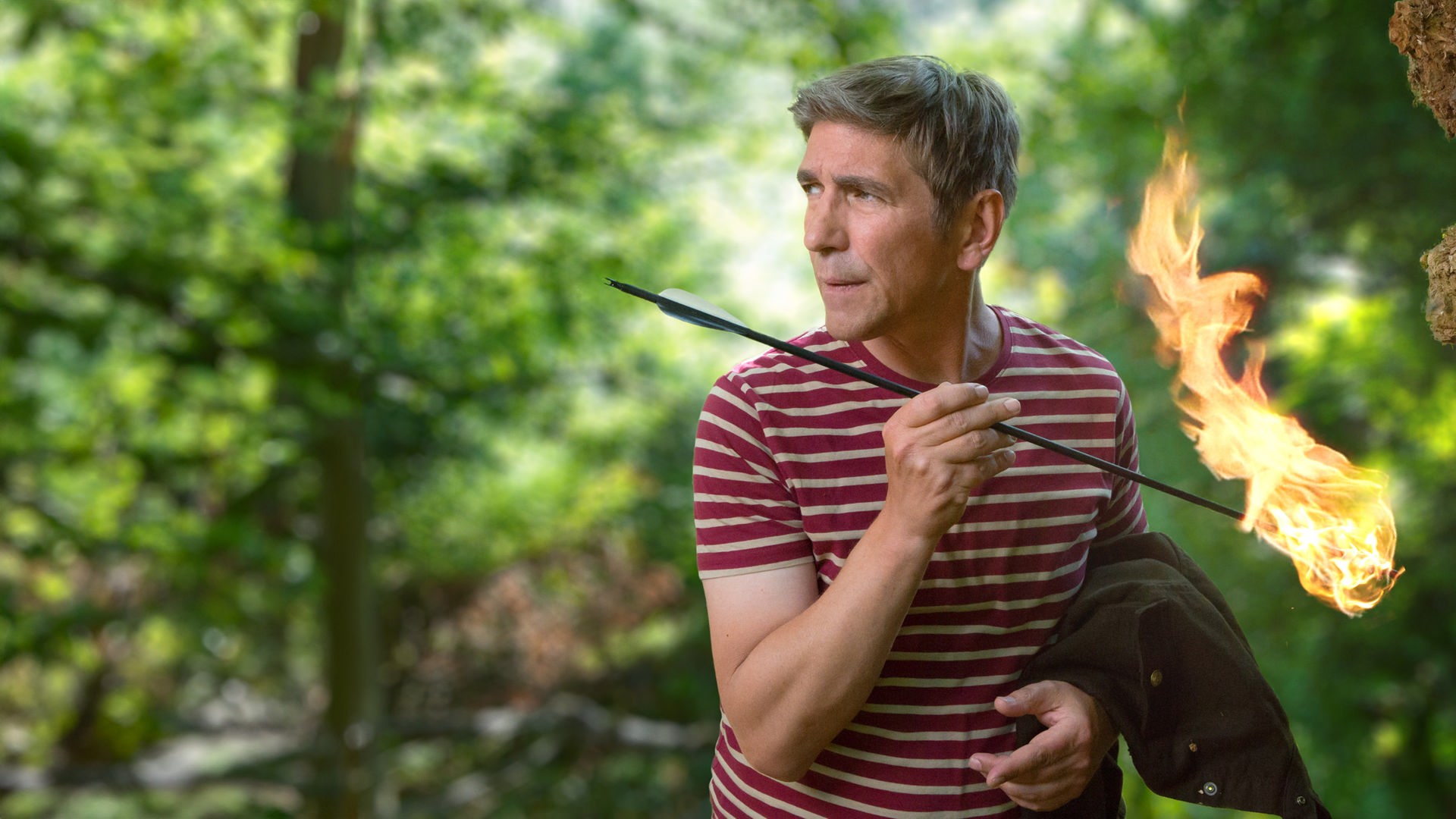 Fritz steht mit einem brennenden Pfeil in der Hand im Wald