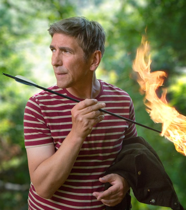 Fritz steht mit einem brennenden Pfeil in der Hand im Wald