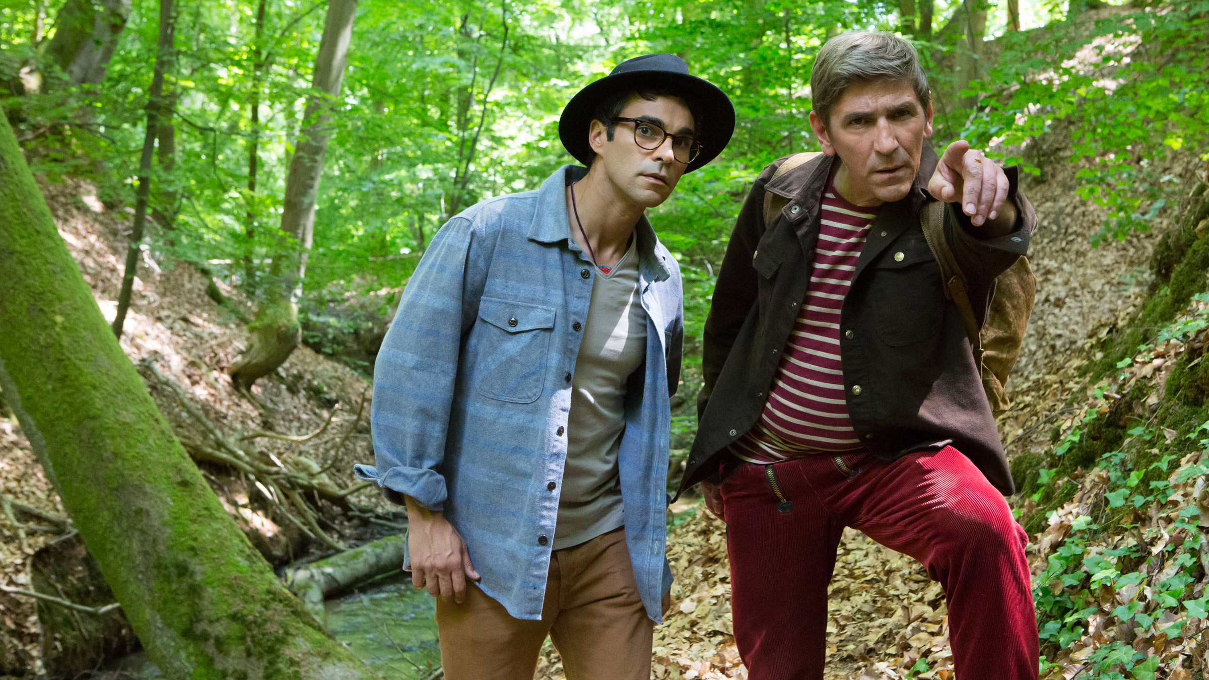 Fritz steht mit  Joseph “Flying Bear” Hawkings im Wald und zeigt mit dem Finger auf etwas