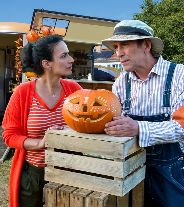Yasemin und Fritz unterhalten sich - zwischen ihnen liegt ein Halloweenkürbis