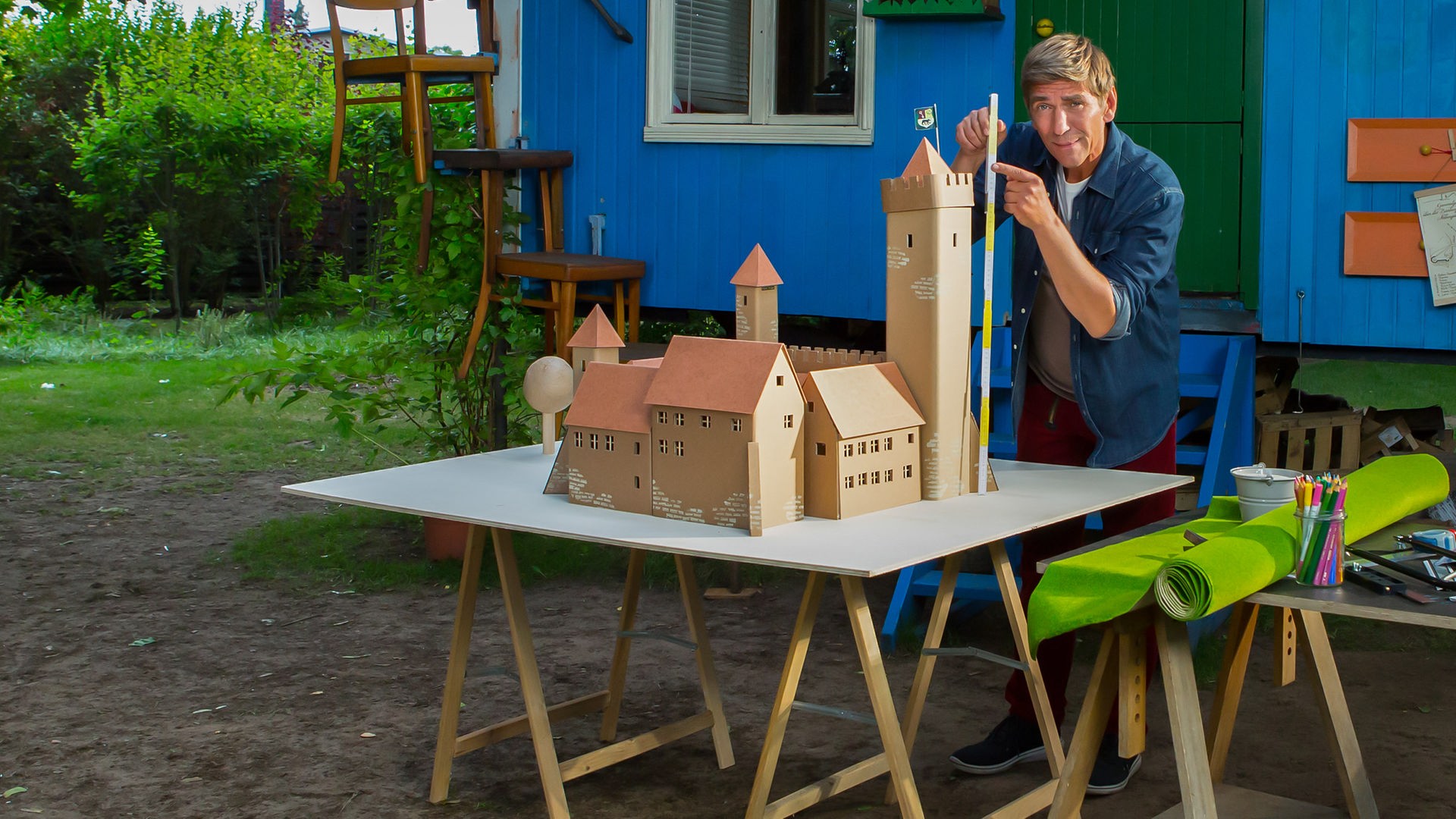 Fritz Fuchs steht vor dem Bauwagen mit einem Metermaß in der Hand