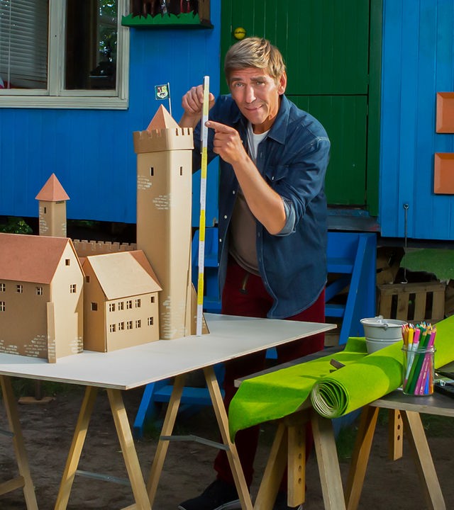 Fritz Fuchs steht vor dem Bauwagen mit einem Metermaß in der Hand