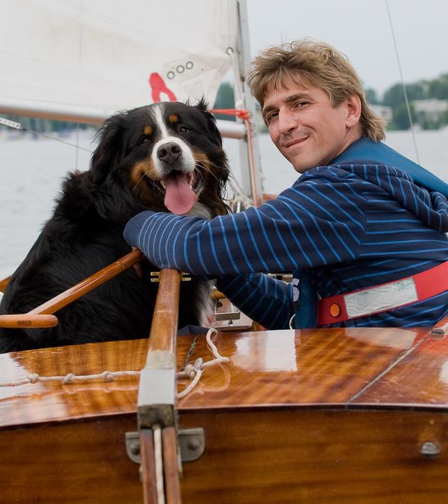 Ein Segelboot mit Fritz und Keks an Bord fährt auf einem See.