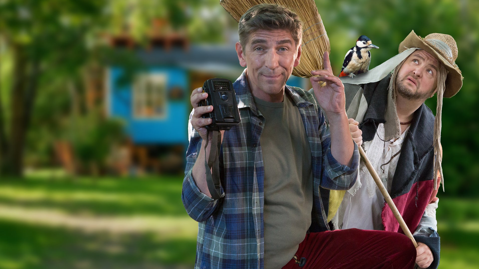 Fritz und David Paschulke, der als Vogelscheuche mit einem Specht auf der Schulter verkleidet ist, stehen vor dem Bauwagen