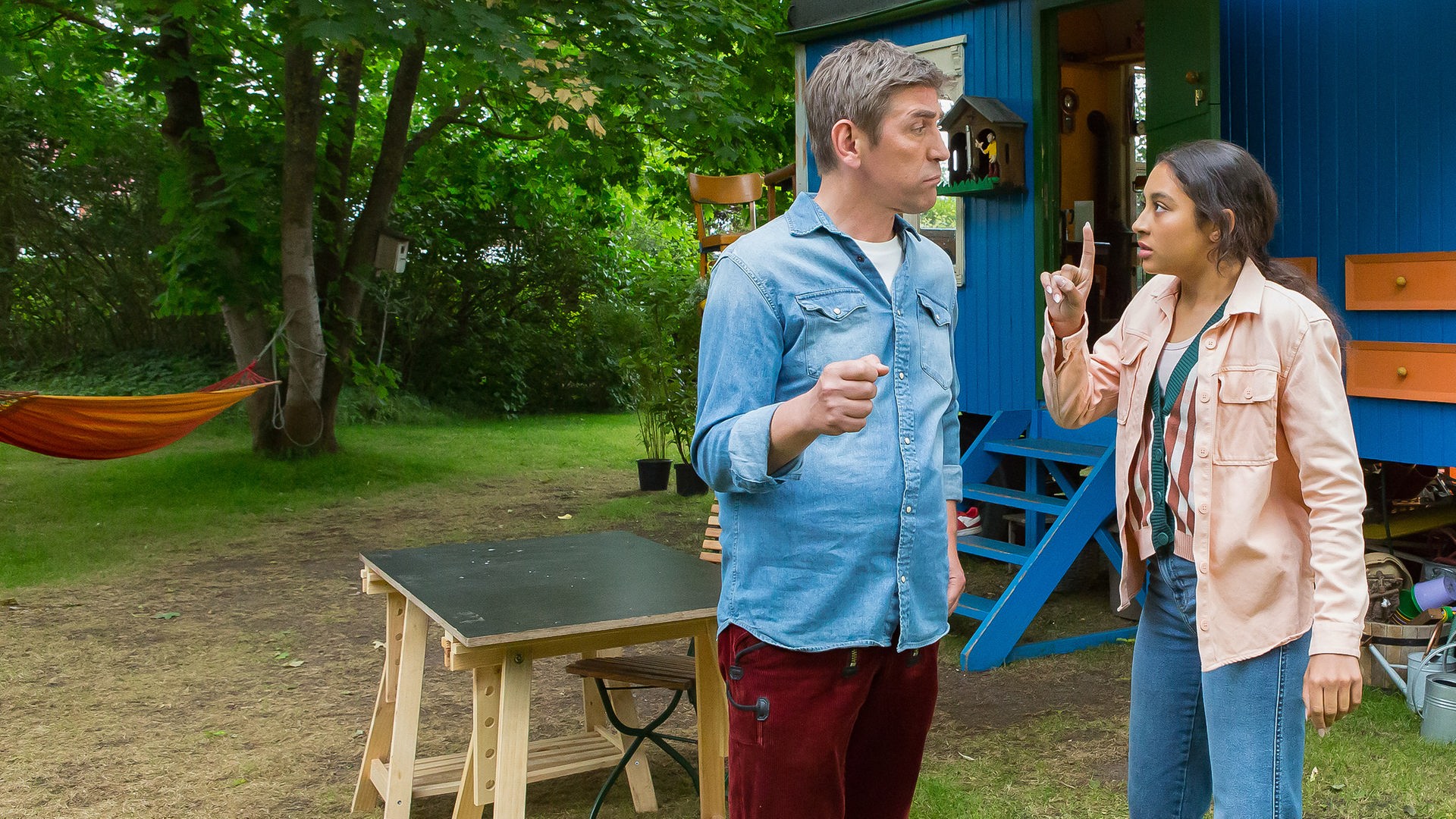 Fritz und Leyla stehen vor dem Bauwagen und unterhalten sich