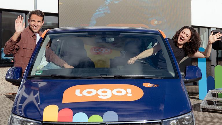 Logo!-Moderator Sherif Rizkallah und Moderatorin  Malral Bazargani winken aus den Seitenfenstern des Logo!-Tour-Busses