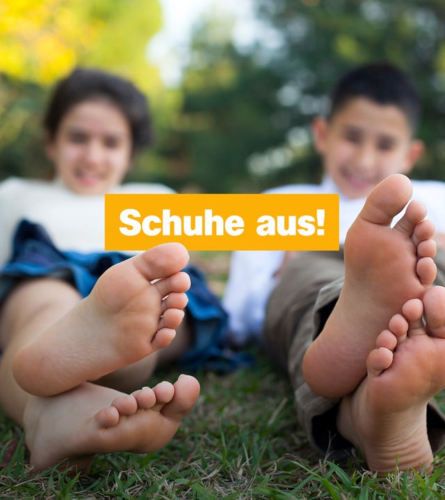 Zwei Kinder strecken ihre Füße aus, darüber steht auf gelbem Hintergrund Schuhe aus!