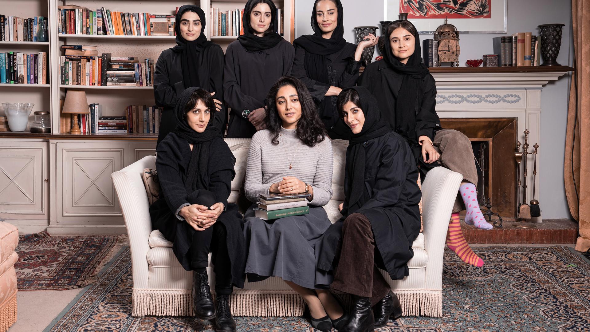 Sieben schwarz gekleidete Frauen, von denen mehrere ein Kopftuch tragen, sitzen in einem Sessel, bzw. stehen dahinter für ein Gruppenfoto.