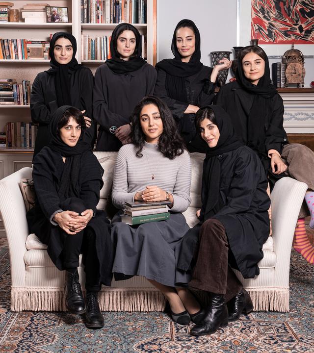 Sieben schwarz gekleidete Frauen, von denen mehrere ein Kopftuch tragen, sitzen in einem Sessel, bzw. stehen dahinter für ein Gruppenfoto.