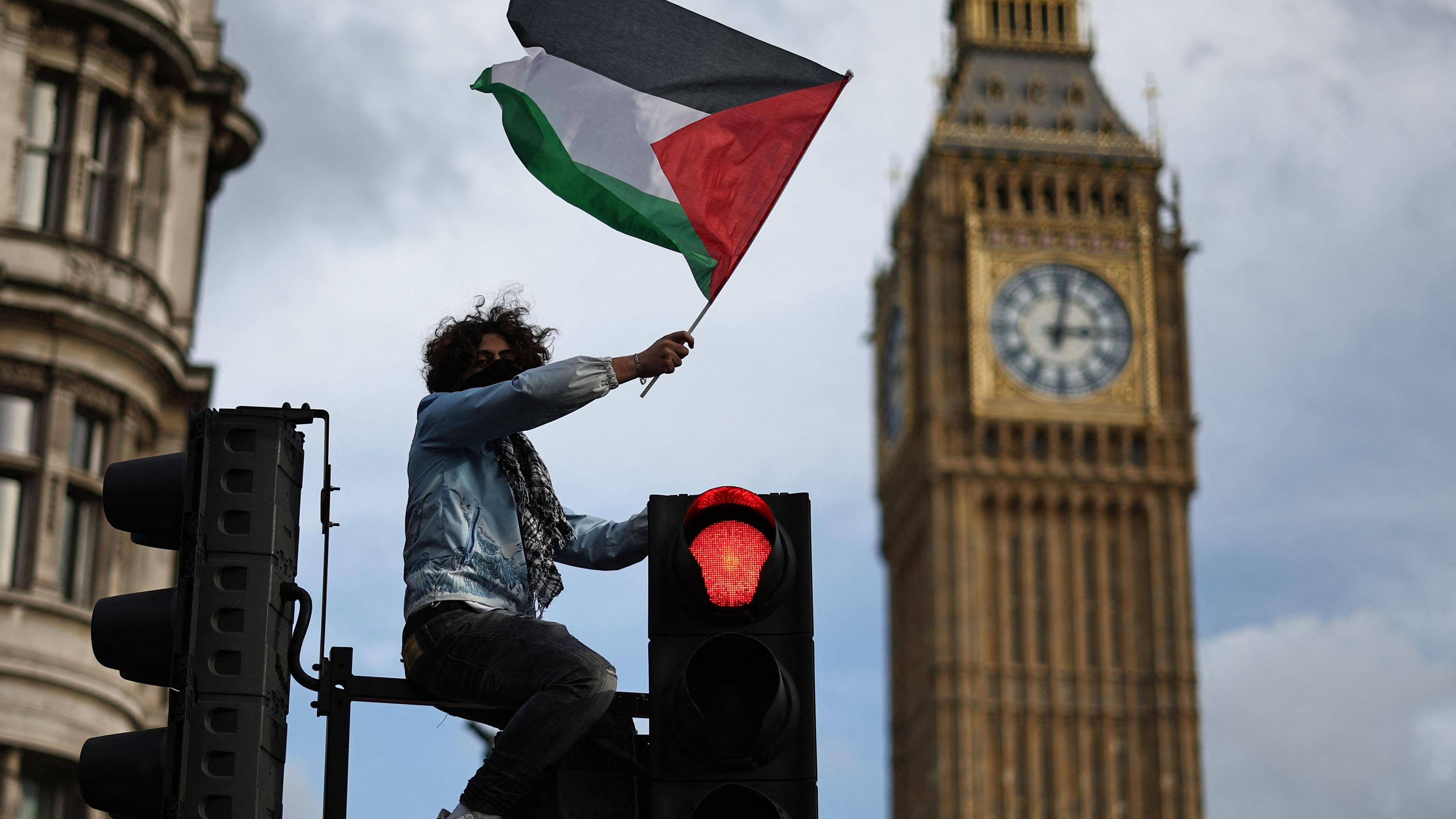 Ein Protestierender mit einer palästinensischen Flagge am Parlamentsplatz in London, bei einer großen Demonstration für Palästina.