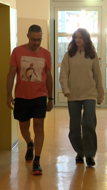 Eine junge Frau und ein Mann gehen einen Gang entlang.