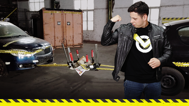 Checkpoint: Cem spannt seinen Bizeps an. Im Hintergrund sind zwei Autos, die mit Seilen und Büchern verbunden sind.