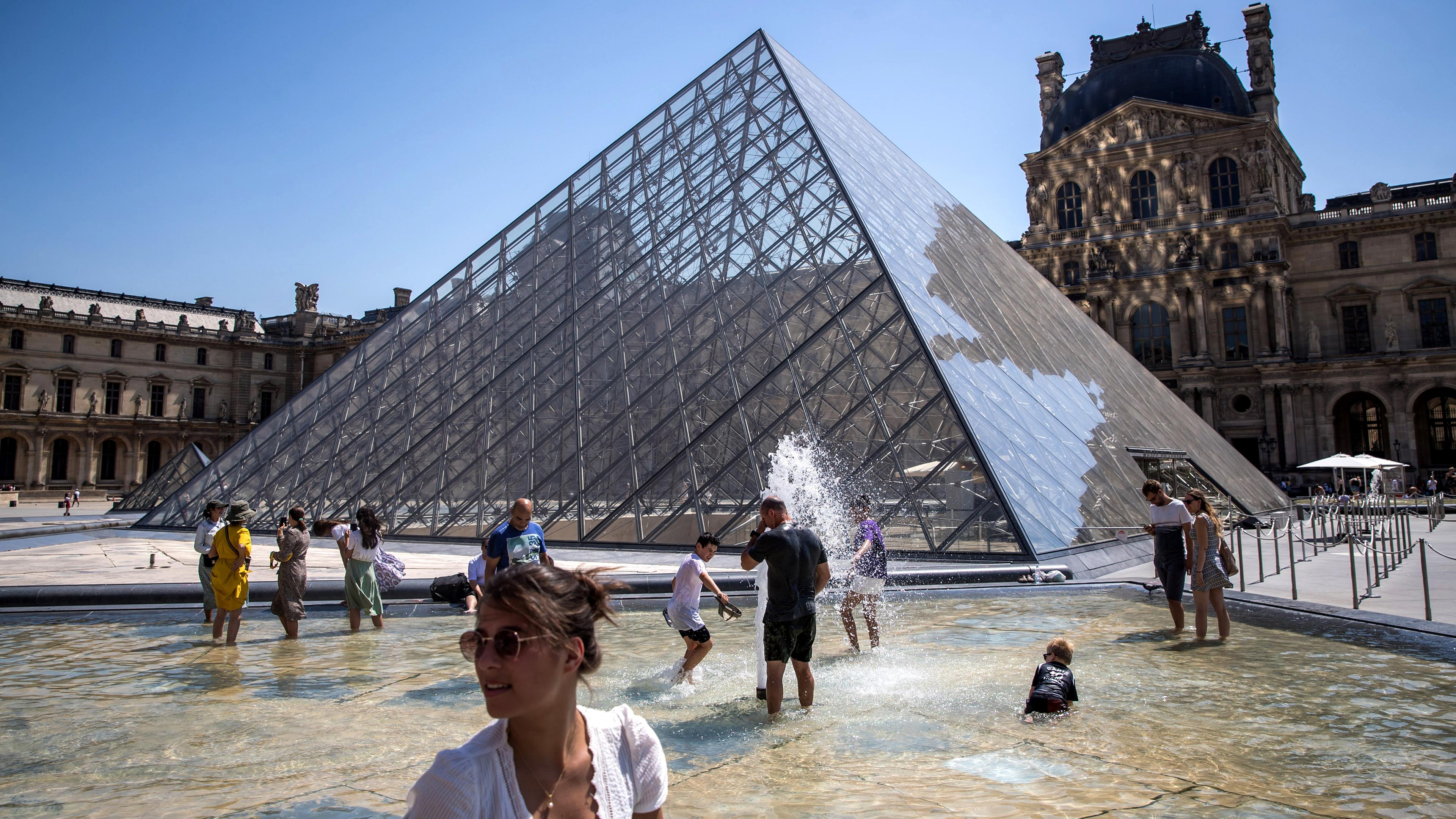 Menschen kühlen sich im Brunnen vor dem Louvre in Paris ab