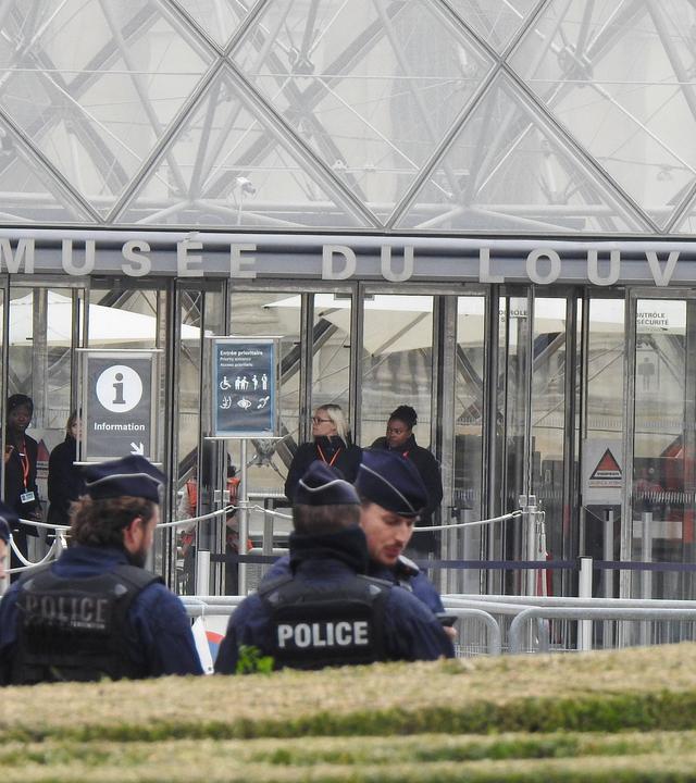 Man sieht Polizeibamte, die vor dem Louvre stehen und den Zugang sperren
